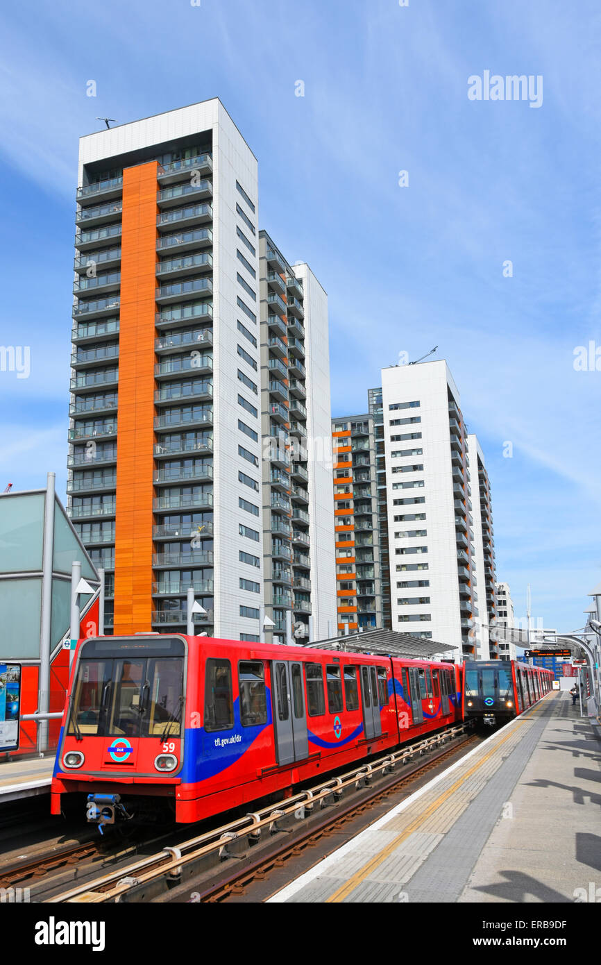 Modern apartment homes in blocks high rise buildings beside Docklands Light Railway trains at East India DLR station platform East London England UK Stock Photo