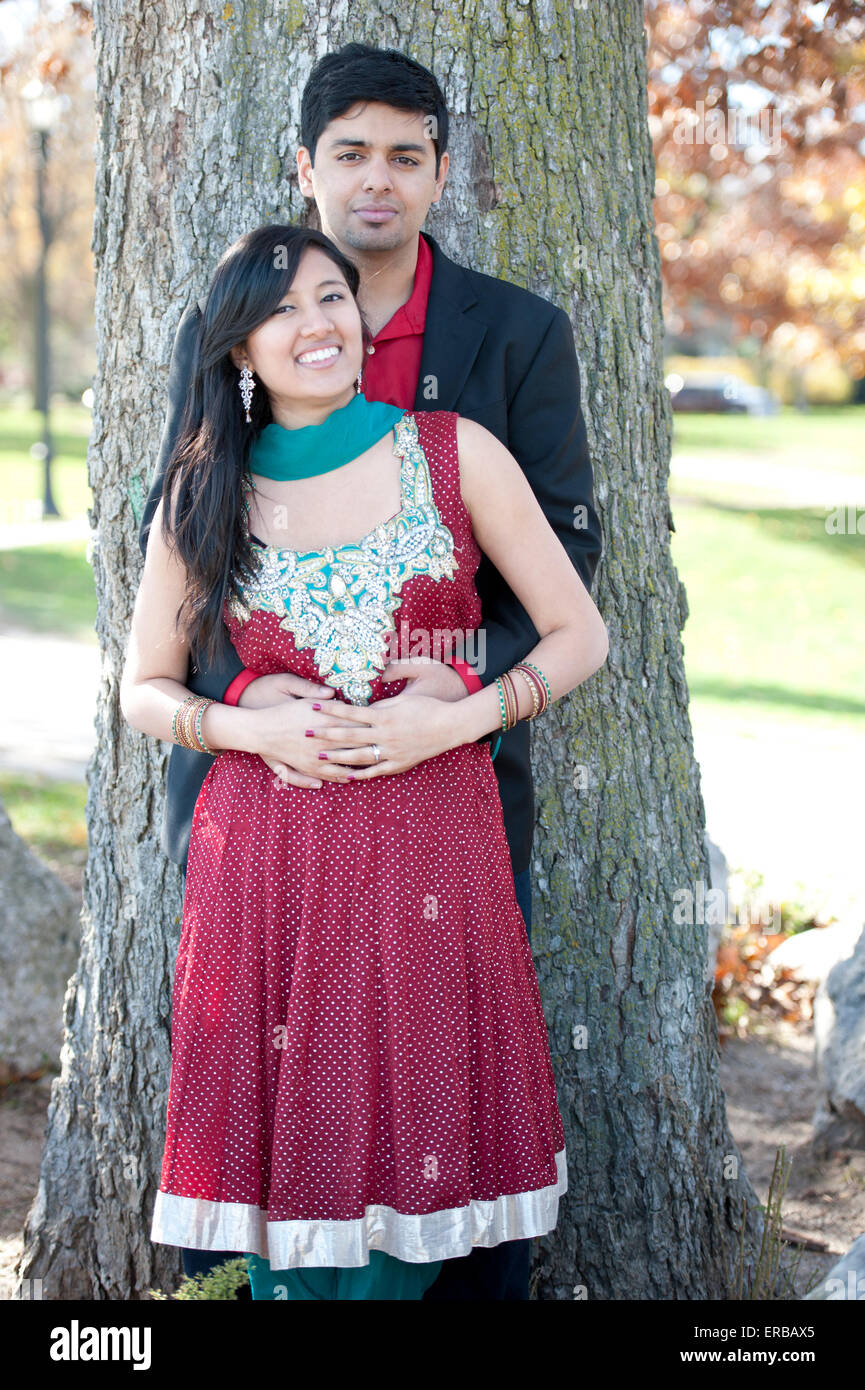 A young and happy Indian couple posing by a tree in the Fall on a sunny ...