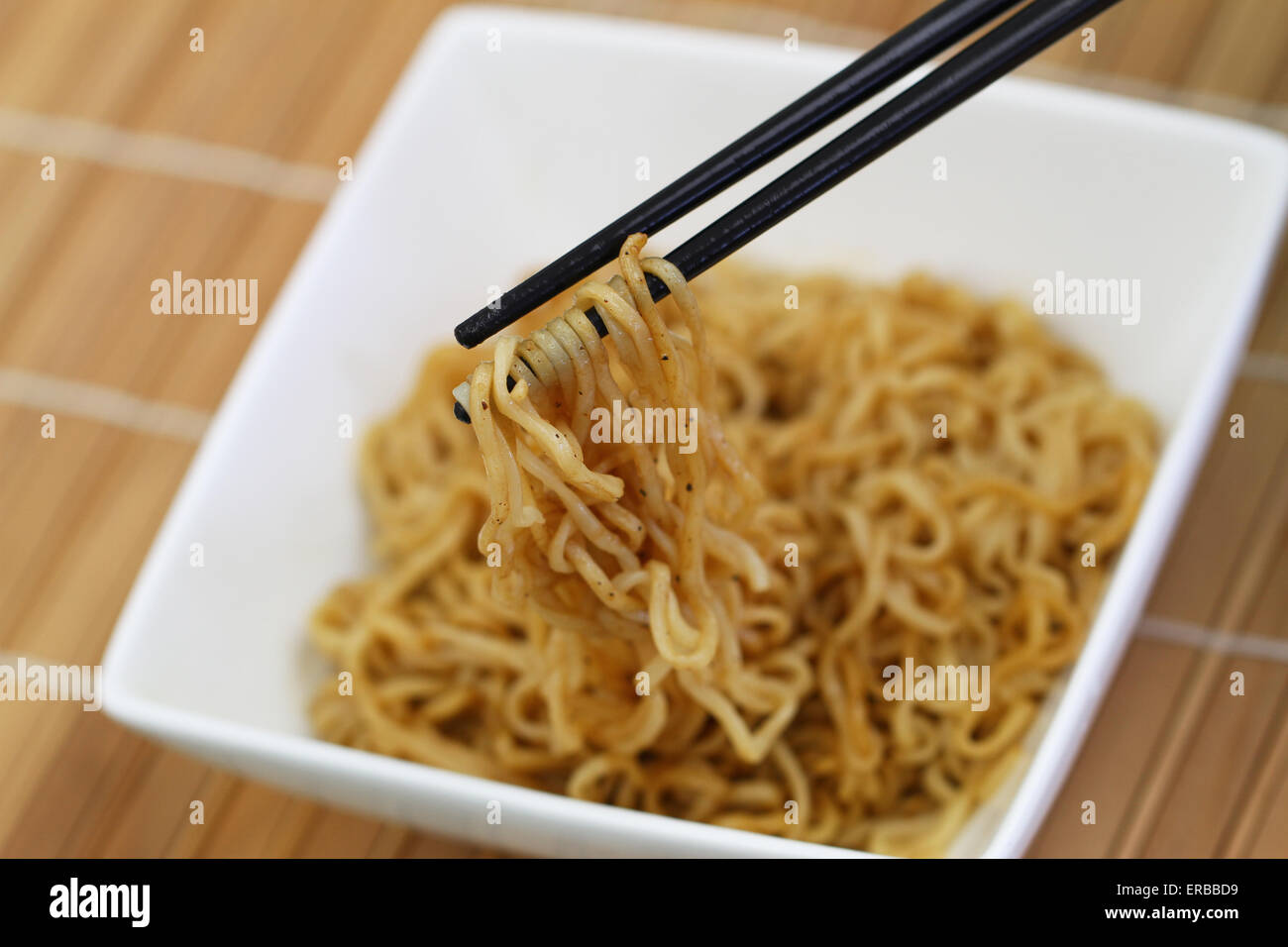 Chinese noodles in bowl and chopsticks on bamboo mat Stock Photo