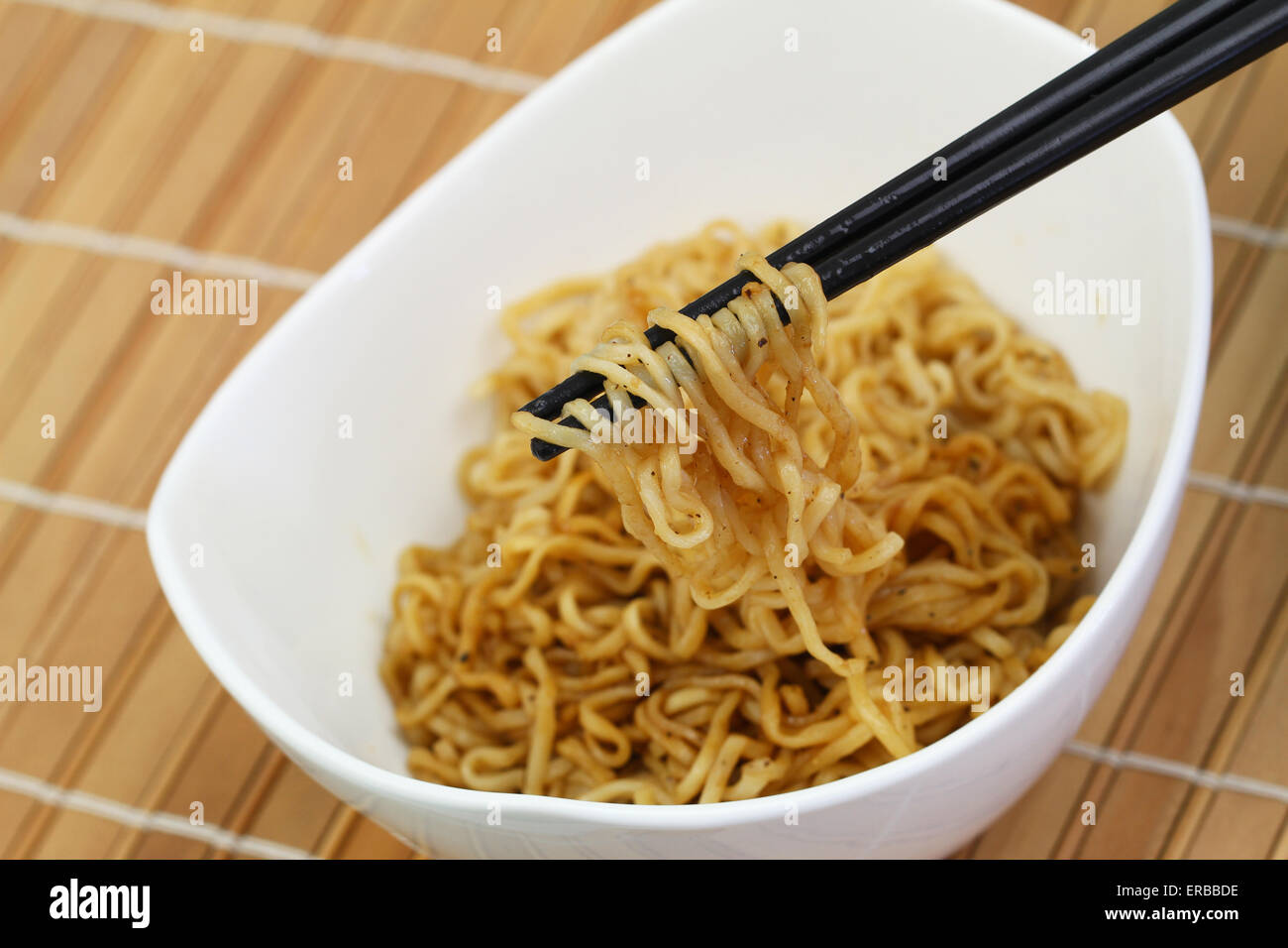 Chinese noodles in bowl and chopsticks on bamboo mat Stock Photo