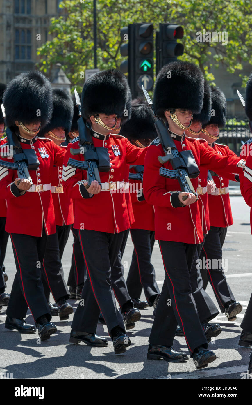 Soldiers from the Grenadier Guards in ceremonial red uniforms marching from the State Opening of Parliament on a sunny day Stock Photo