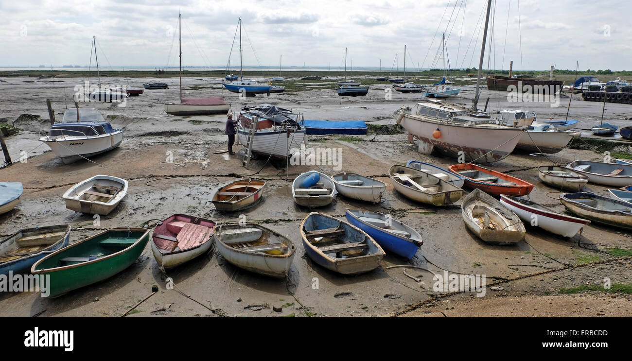 Sail Boats with the tide out on the estuary Leigh on Sea Essex UK. Man is painting his boat. Stock Photo