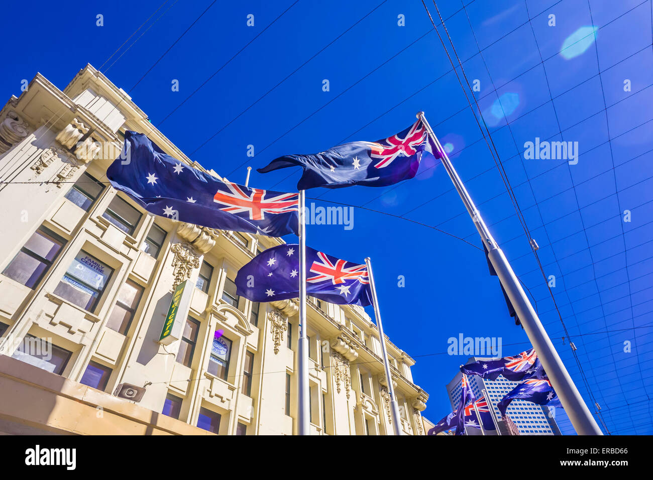 Looking up toward bright blue sky, Australian flags wave in the breeze