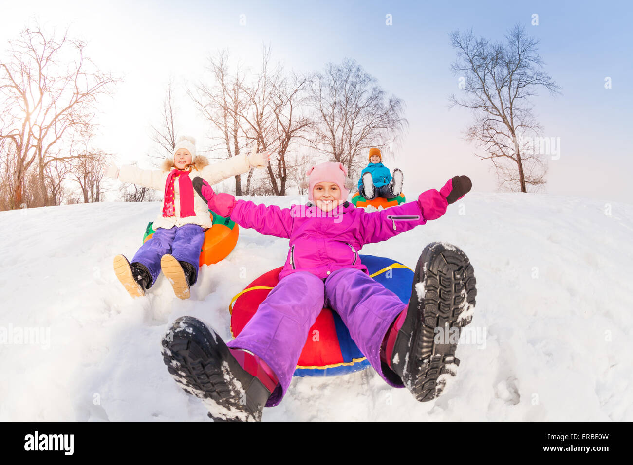 Girl and her friends sliding down hill on tubes Stock Photo