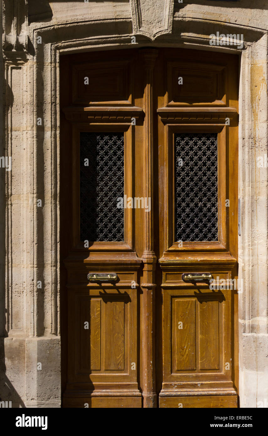 A traditional wooden entrance doorway with a decorated stone surround in sunshine, Montmartre, Paris, France Stock Photo