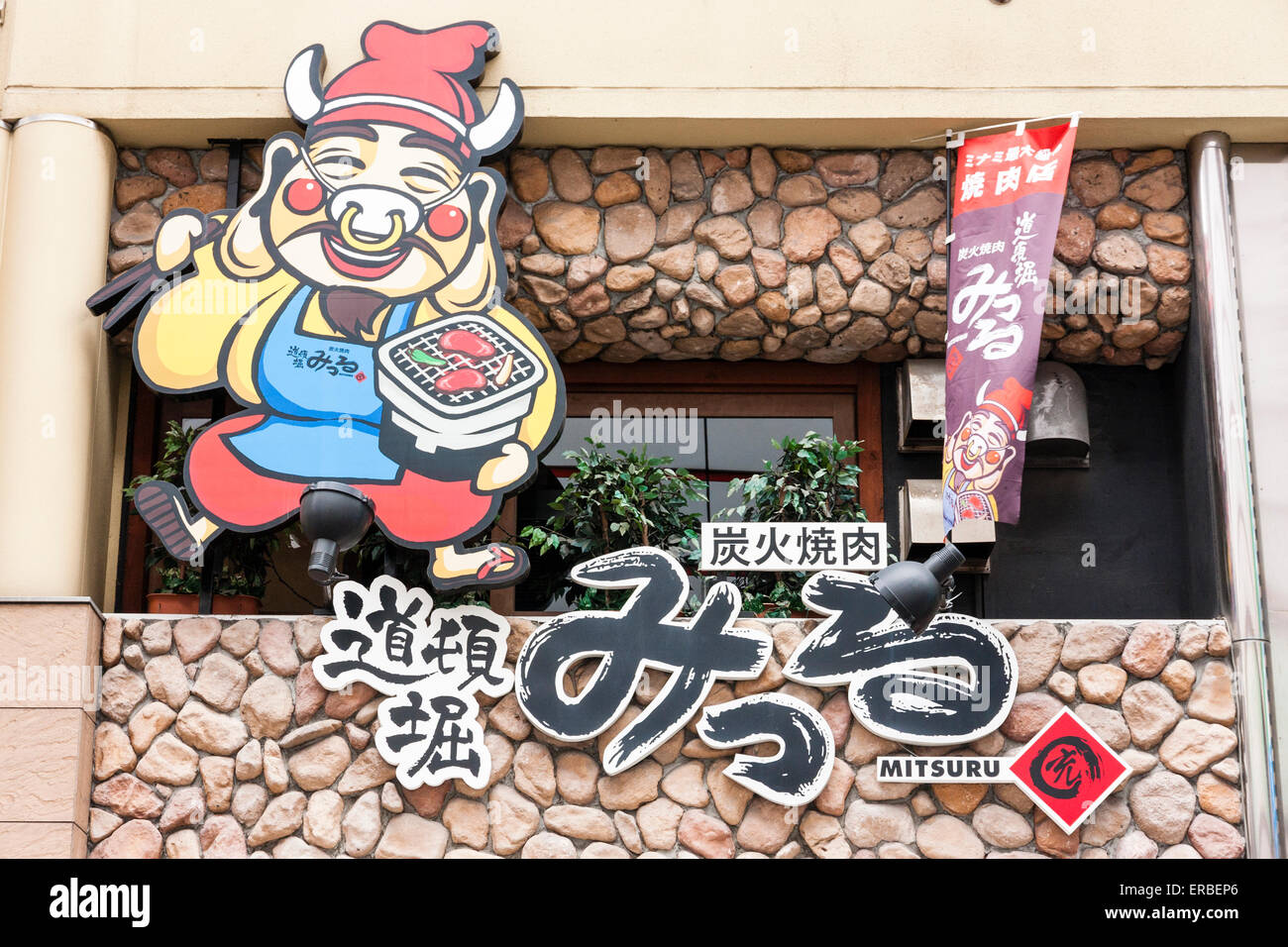 Balcony of the Yakiniku Mirru with the large logo sign featuring a laughing walking dressed pig carrying a small coal barbecue box. Stock Photo