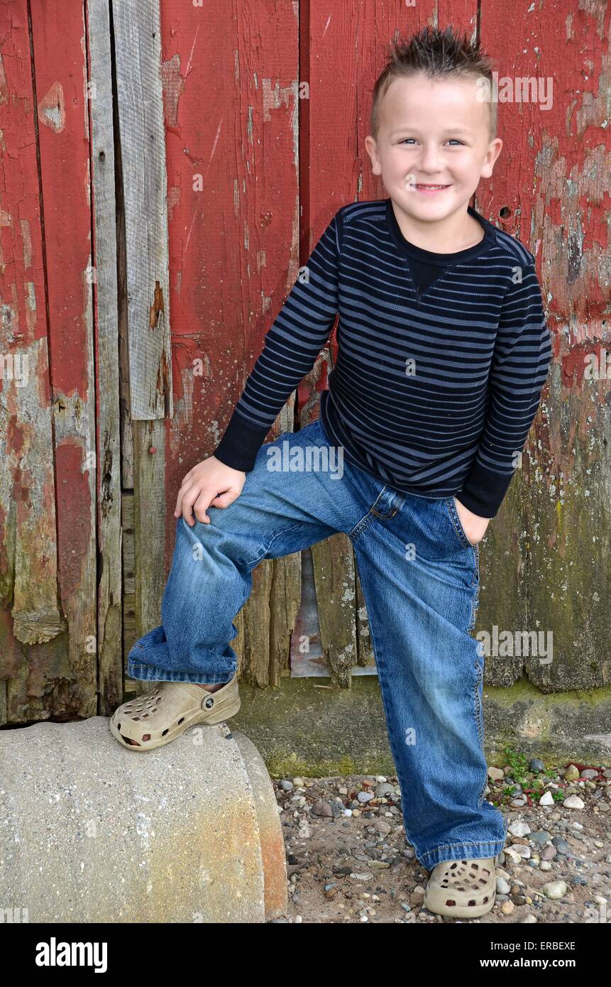 Young Caucasian boy by old red barn Stock Photo - Alamy