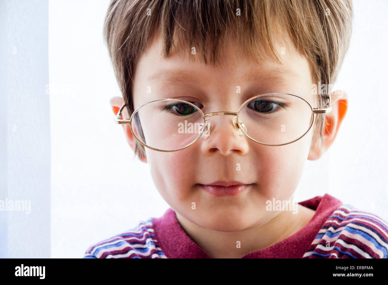 Face shot, close up of cute young child, boy with brown hair 4-5 year old,  looking down and smiling while wearing a pair of spectacles, glasses Stock  Photo - Alamy