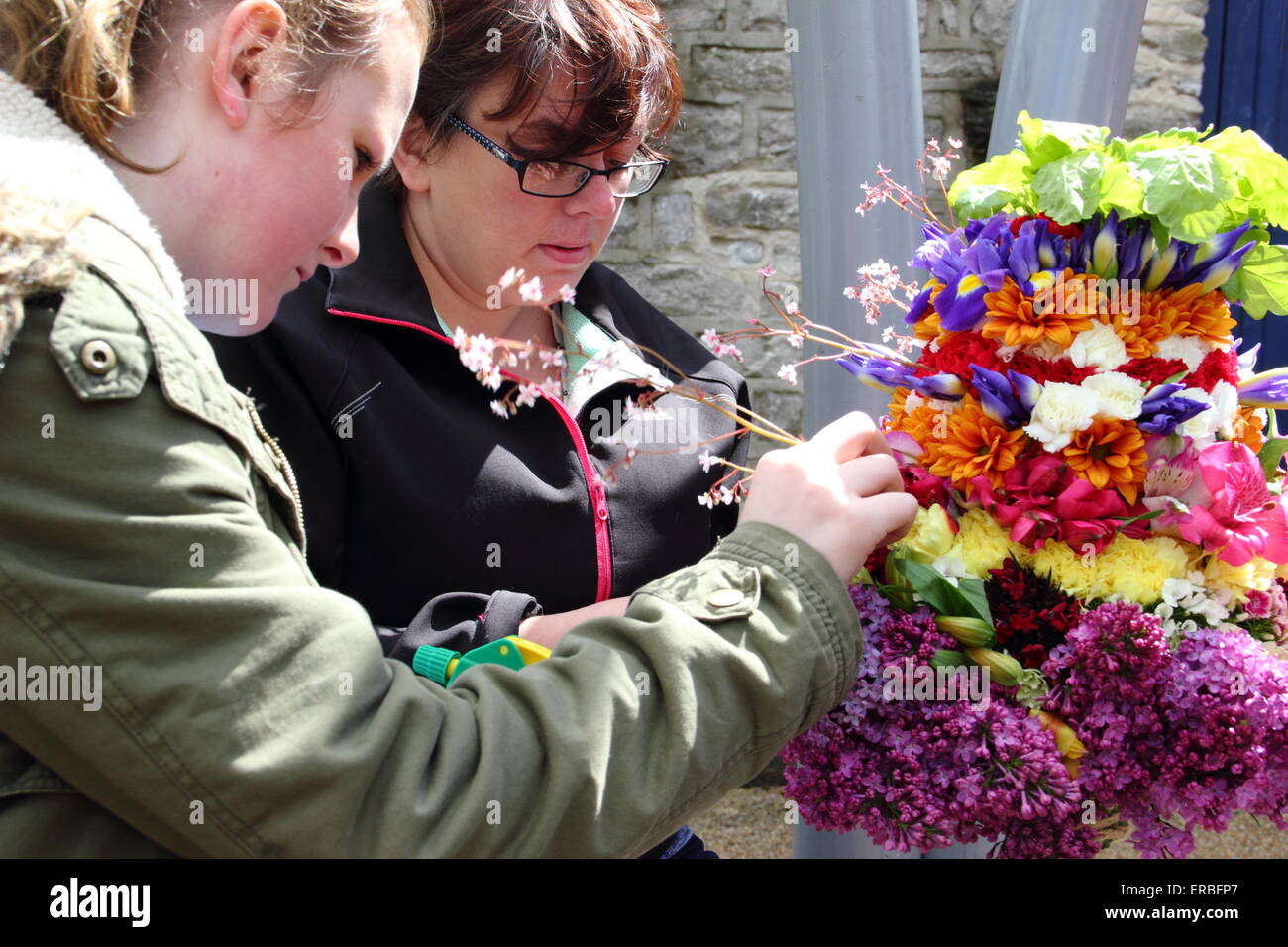 Garland makers put the finishing touches to the floral headdress worn by the Garland King to celebrate Oak Apple Day, Castleton Stock Photo