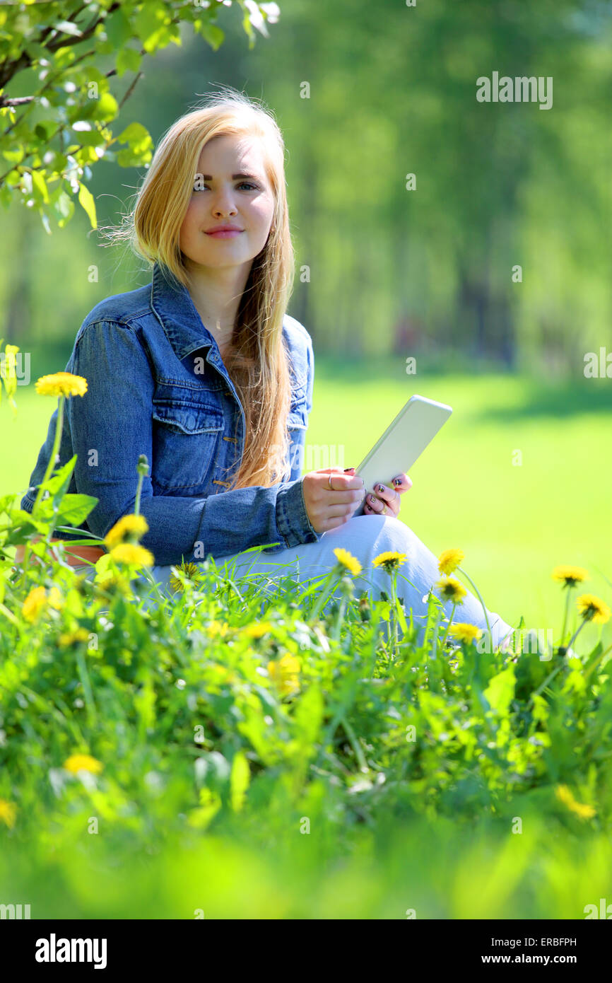 Young woman using tablet in spring park with flowers Stock Photo