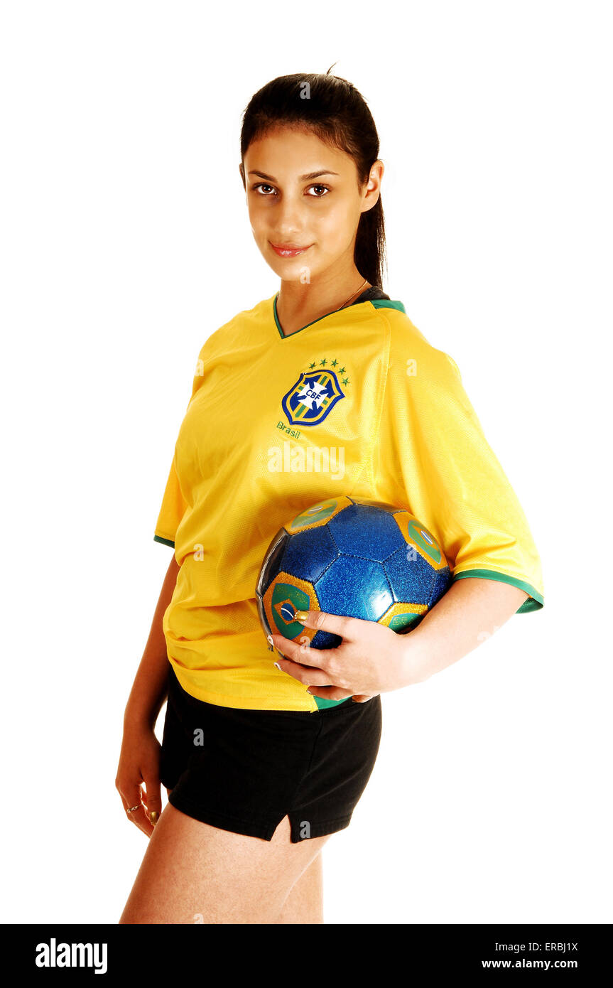 A young pretty soccer girl standing in her uniform, yellow top and
