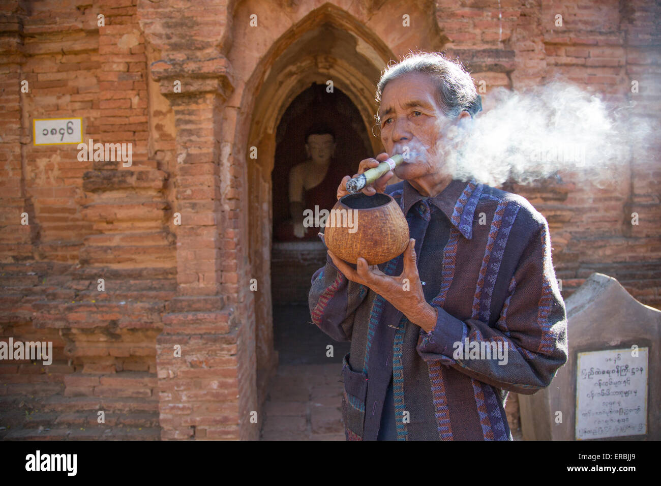 Lady smoking cheroot at Khay Min Gha temple in Bagan Myanmar Stock Photo