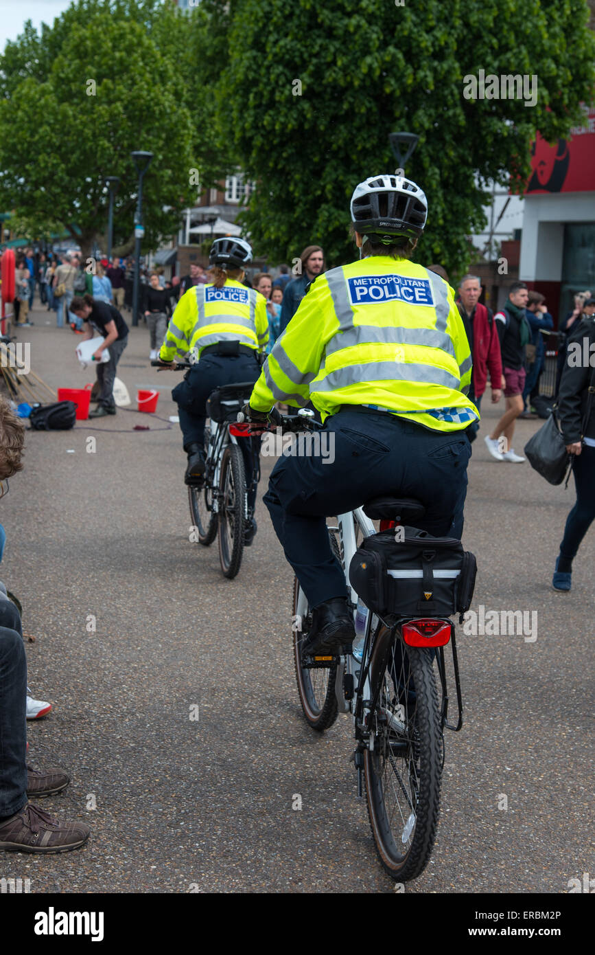 Two Metropolitan Police Officers patrol the South Bank of the River Thames by bicycle. Stock Photo