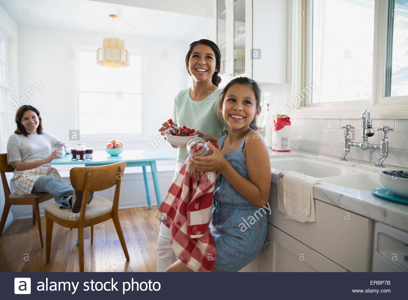 Smiling girls making jam with berries in kitchen Stock Photo