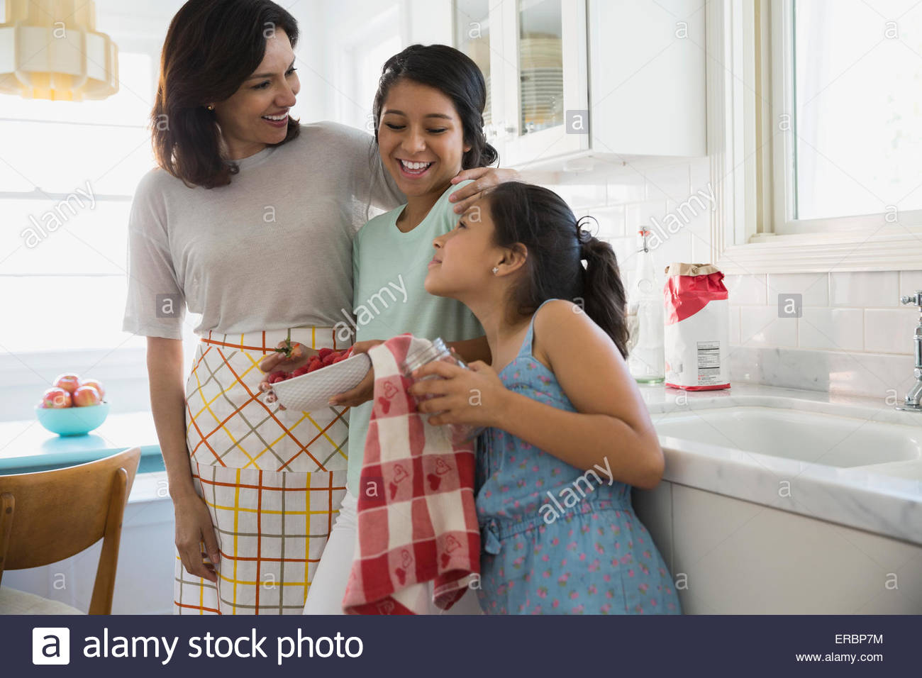 Mother and daughters hugging in kitchen Stock Photo