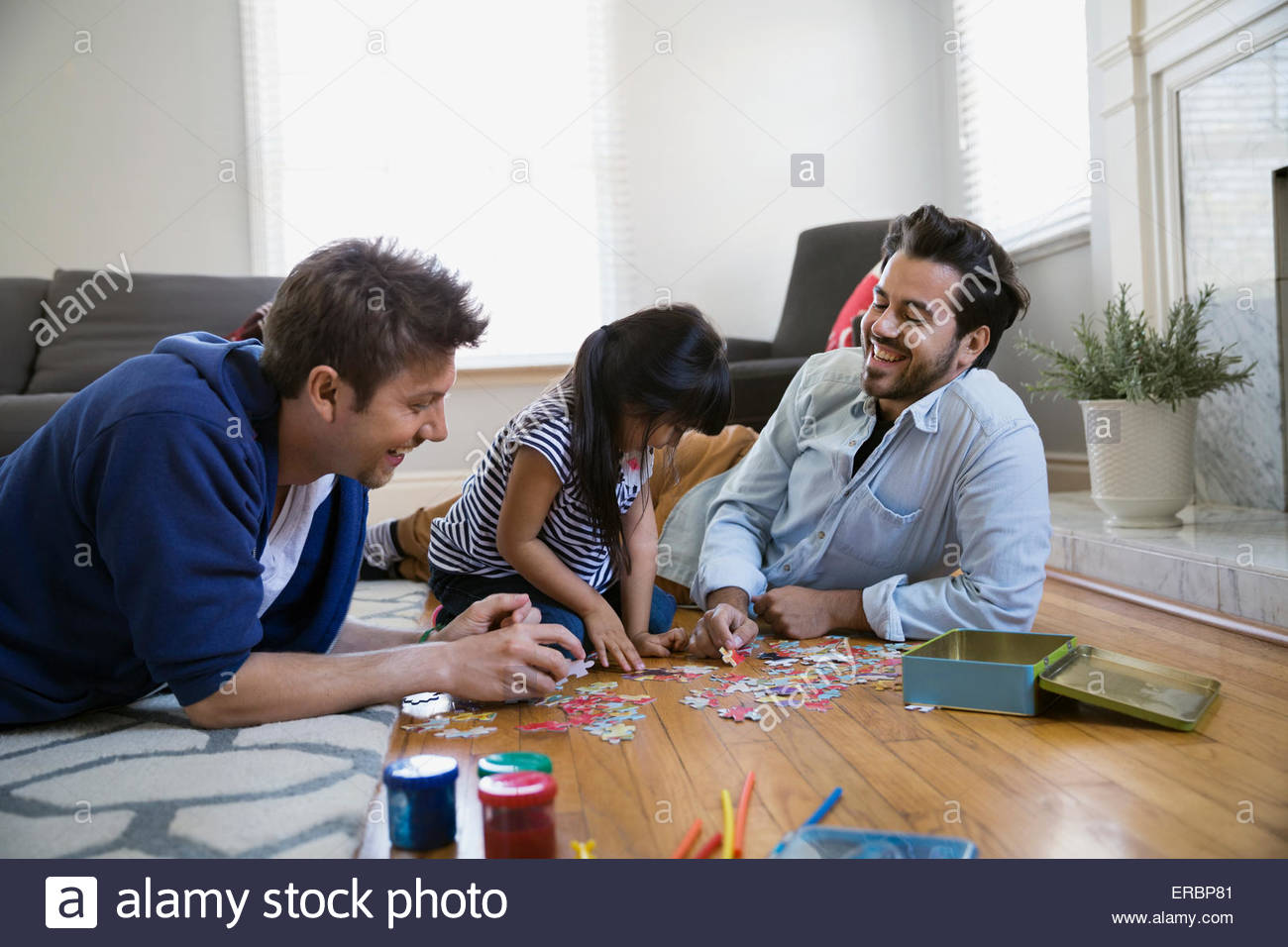 Homosexual couple and daughter assembling jigsaw puzzle Stock Photo