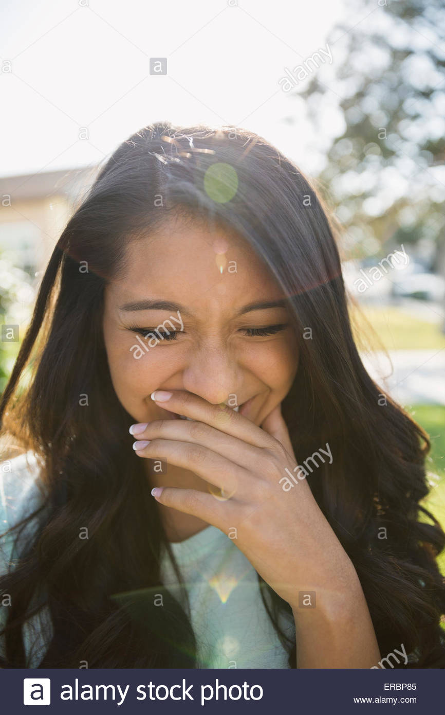 Close up brunette teenage girl laughing sunny yard Stock Photo