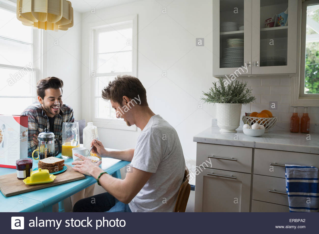 Homosexual couple enjoying breakfast at kitchen table Stock Photo