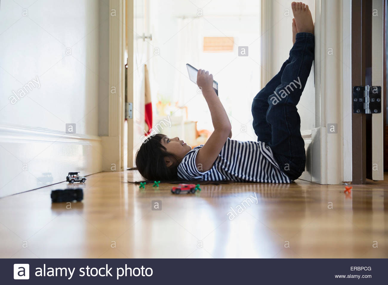 Brunette girl using digital tablet legs up wall Stock Photo