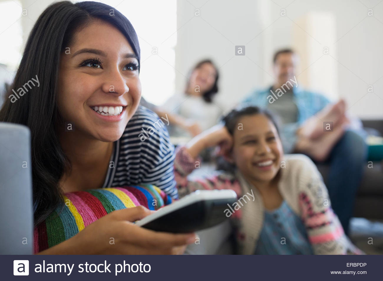 Smiling teenage girl watching TV with family Stock Photo