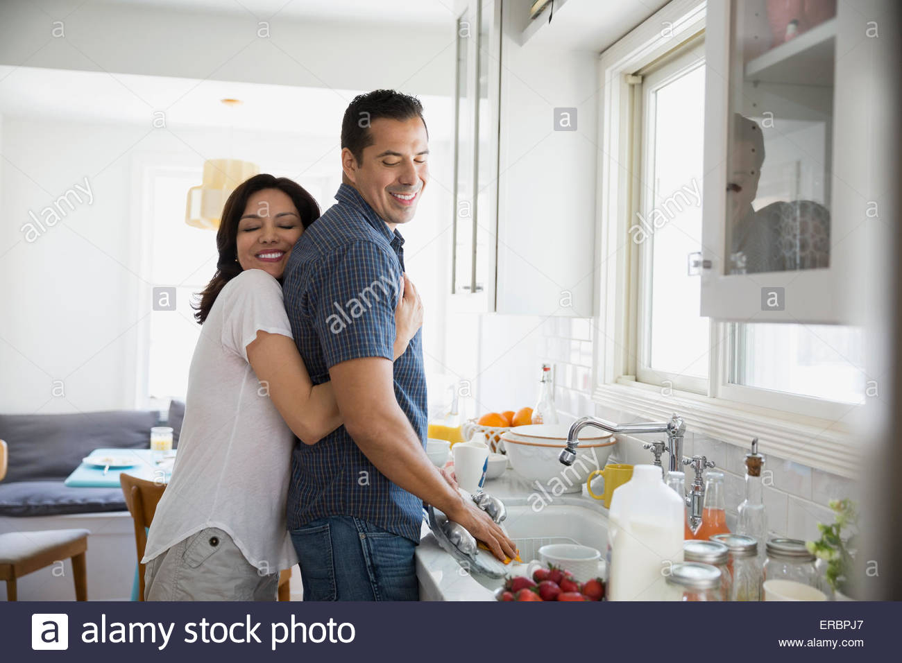 Affectionate brunette couple hugging at kitchen sink Stock Photo - Alamy