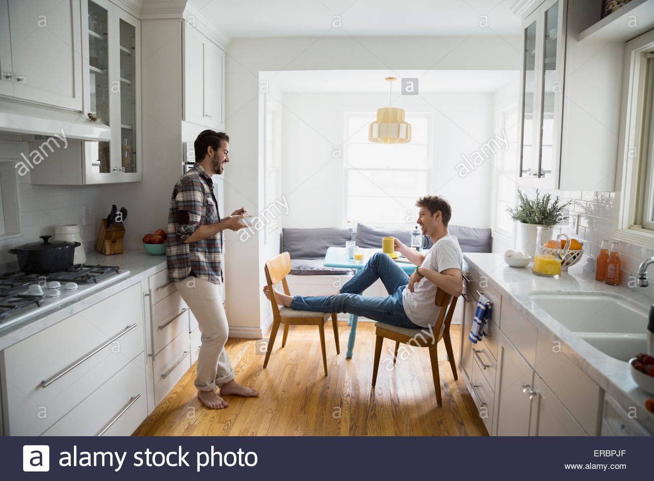 Homosexual couple talking and eating breakfast in kitchen Stock Photo