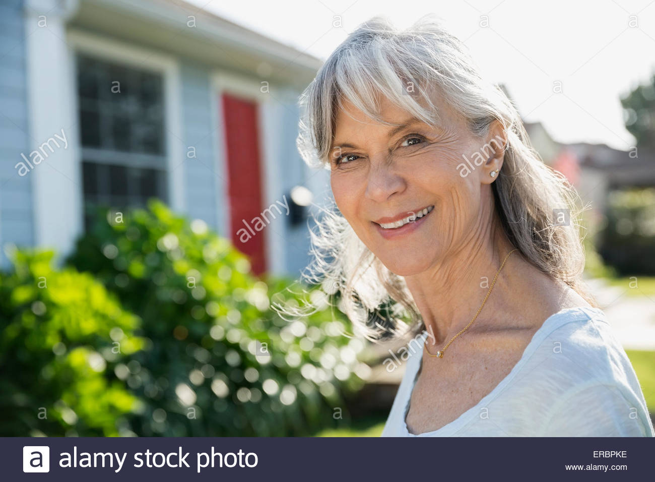 Portrait smiling senior woman in sunny front yard Stock Photo - Alamy
