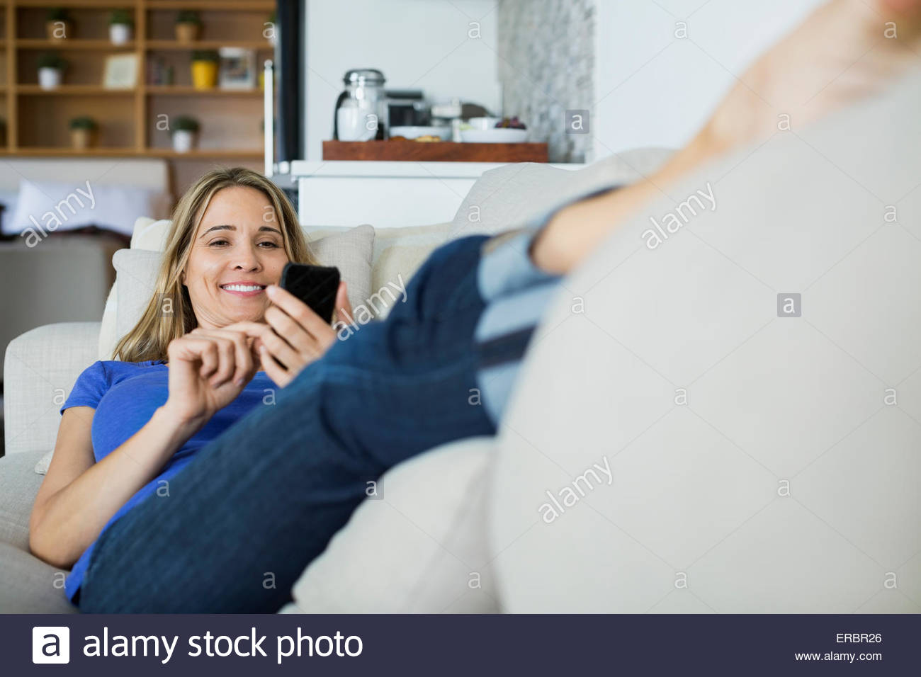 relaxed-woman-texting-with-cell-phone-on-sofa-ERBR26.jpg
