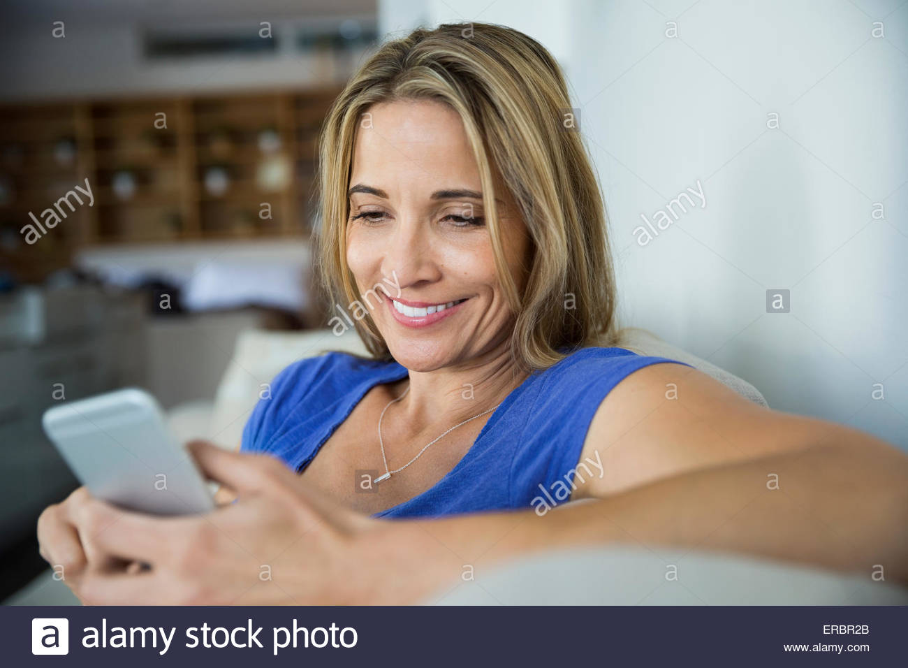 Smiling blonde woman texting with cell phone Stock Photo