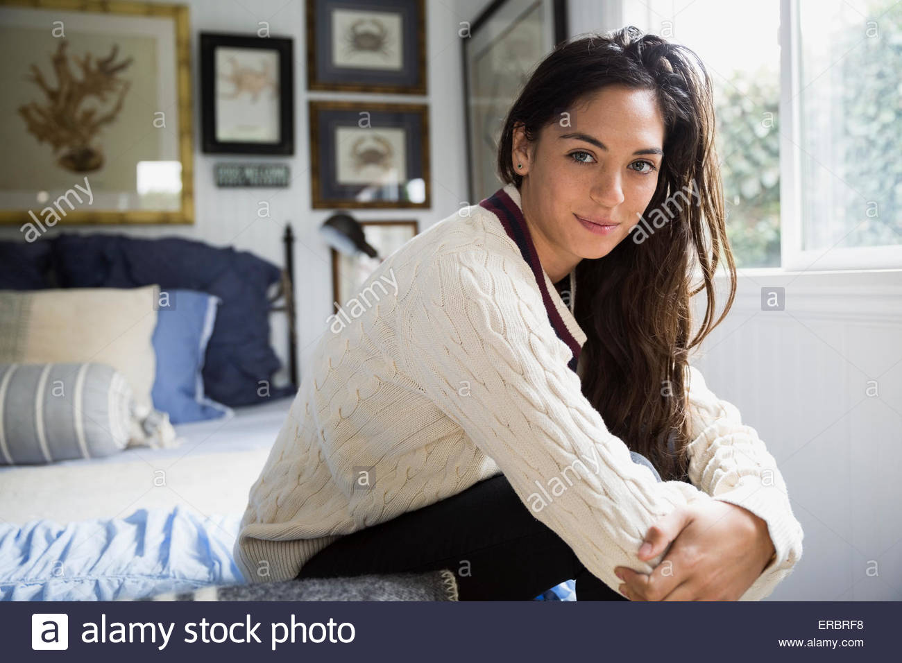 Portrait brunette woman hugging knees on bed Stock Photo