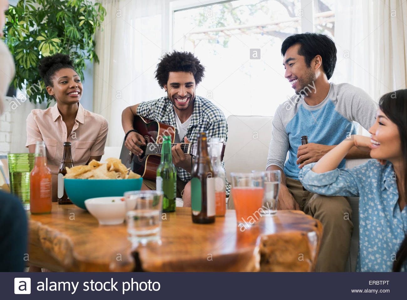 Friends hanging out playing guitar in living room Stock Photo