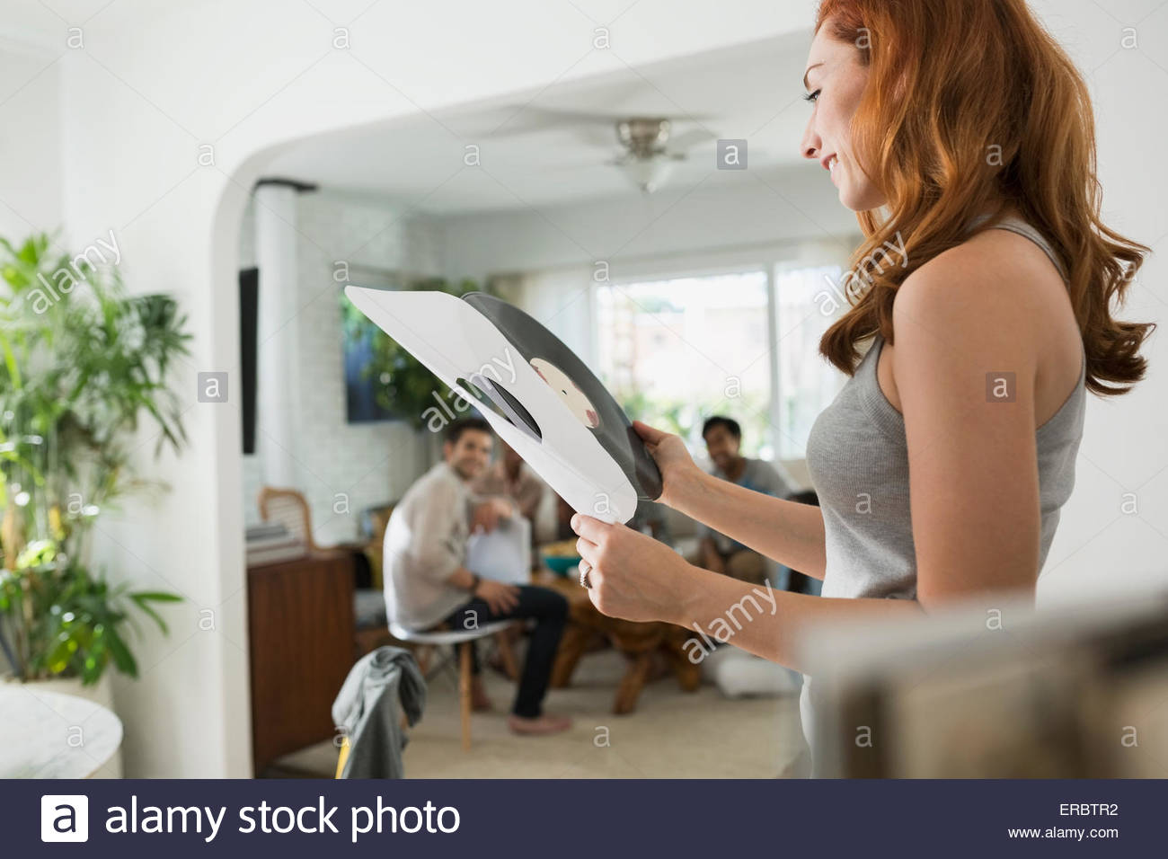 Smiling woman looking at vinyl music record Stock Photo