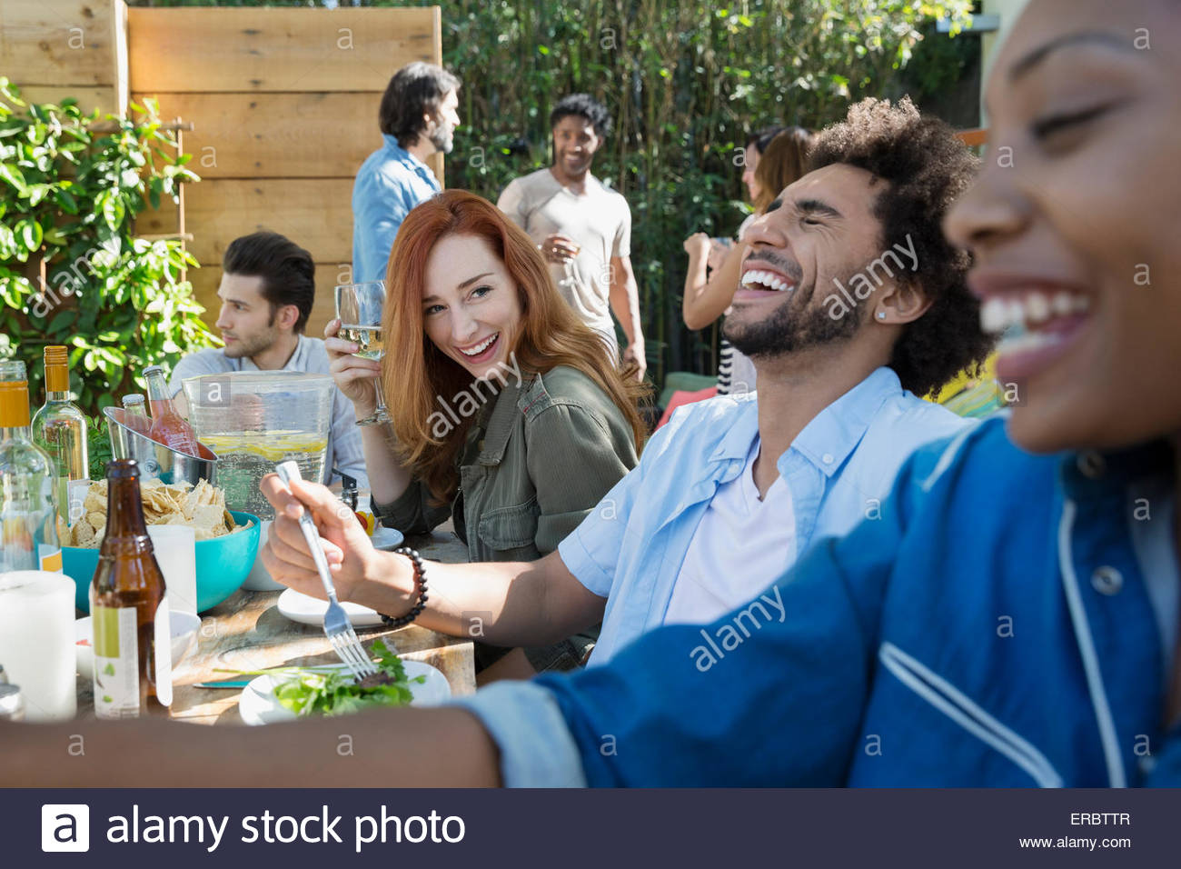 Friends laughing eating and drinking at patio table Stock Photo Alamy