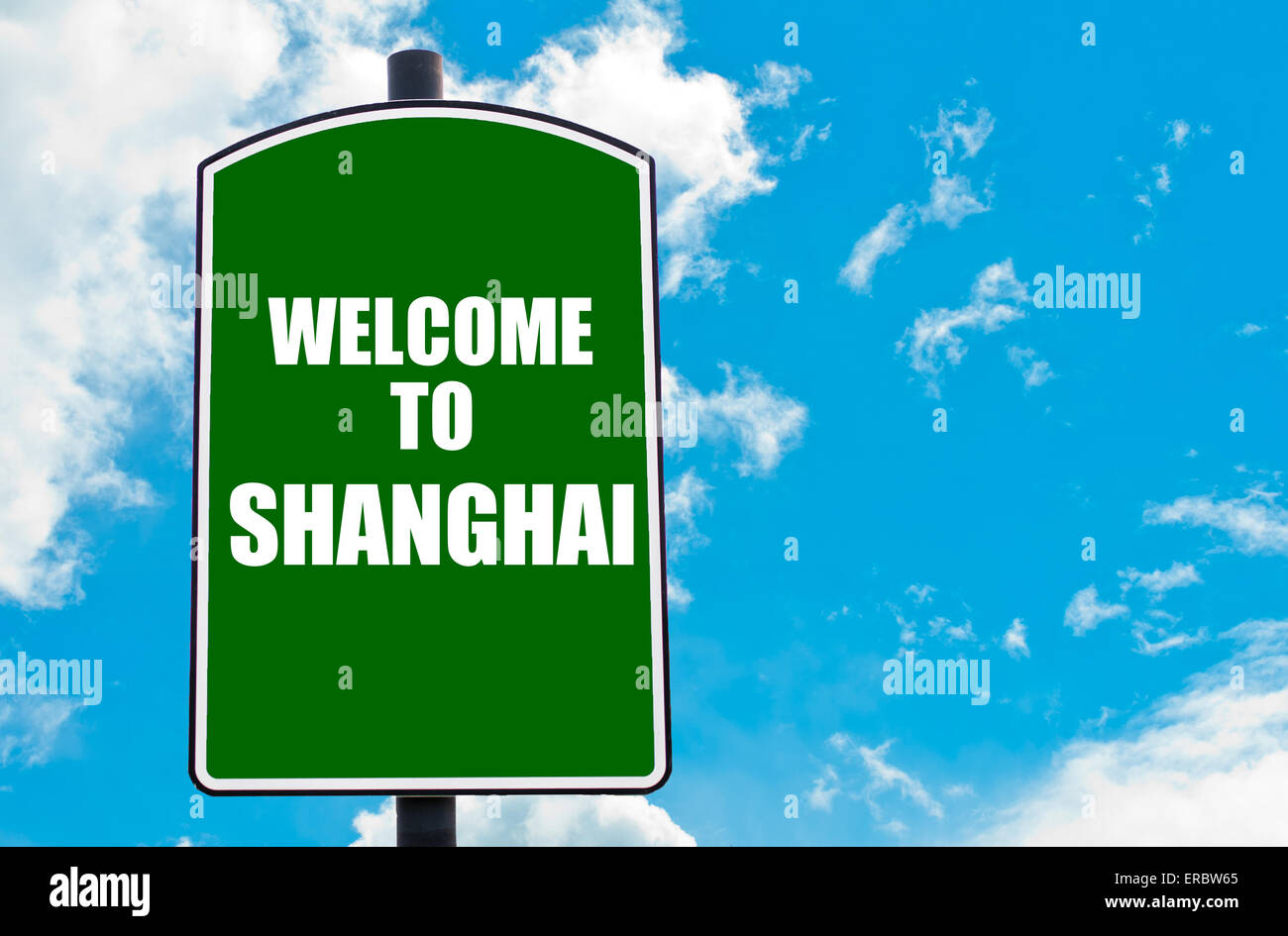 Green road sign with greeting message WELCOME TO SHANGHAI, CHINA isolated over clear blue sky background Stock Photo