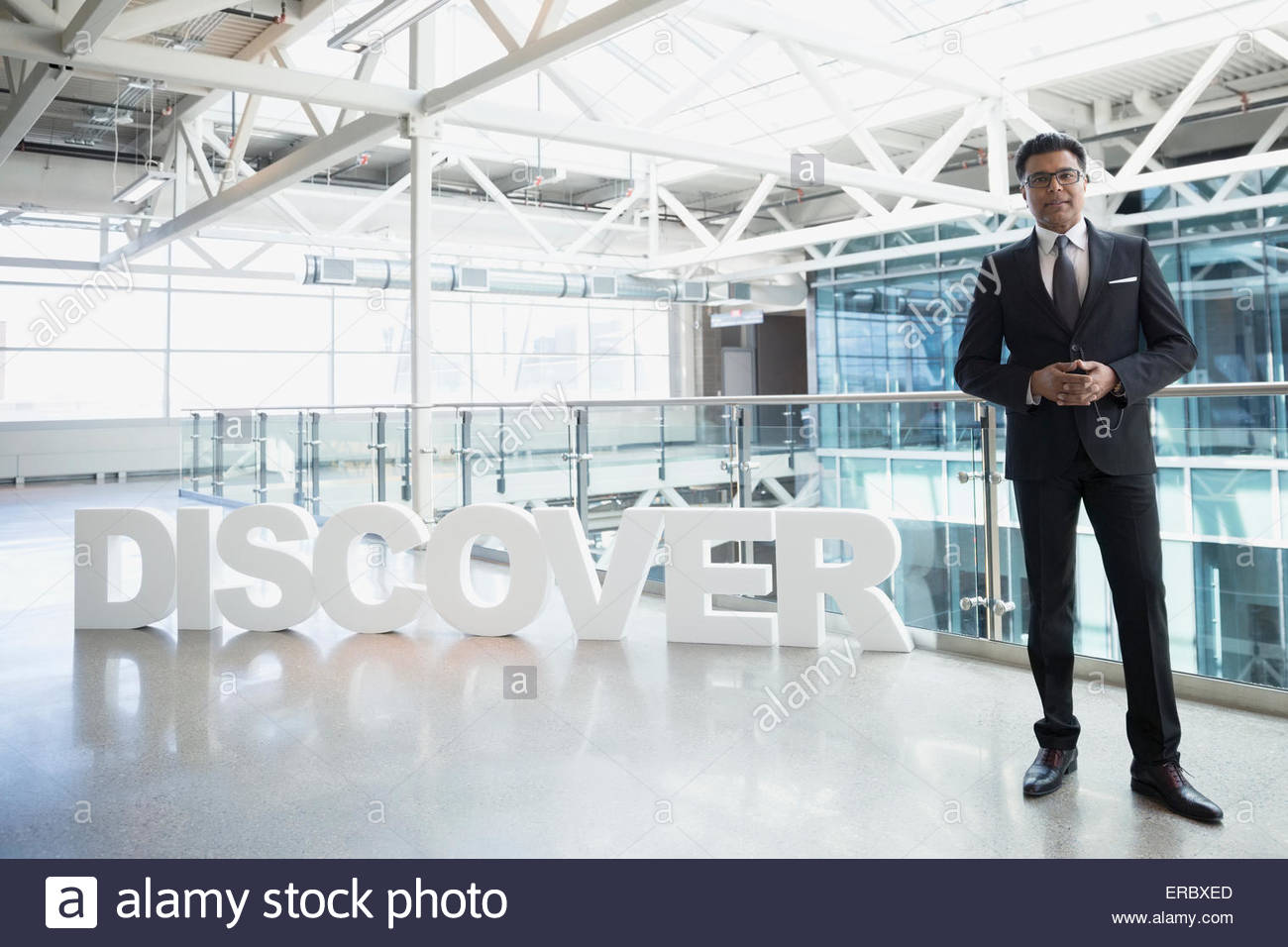 Portrait confident businessman next to 'Discover' text atrium Stock Photo