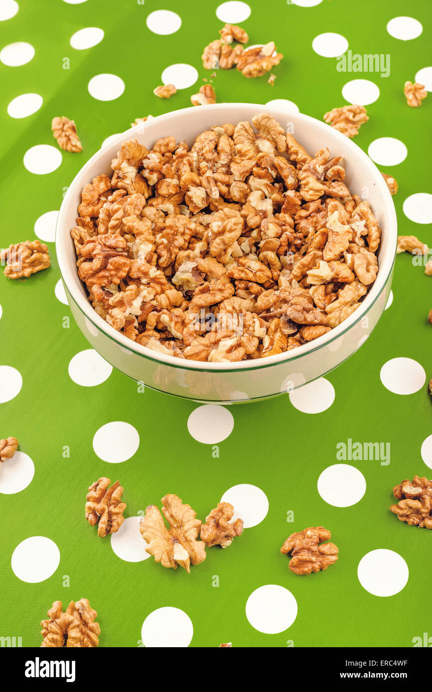 Peeled Walnut Kernels in Ceramic Bowl on Green Polka Dotted Background Stock Photo
