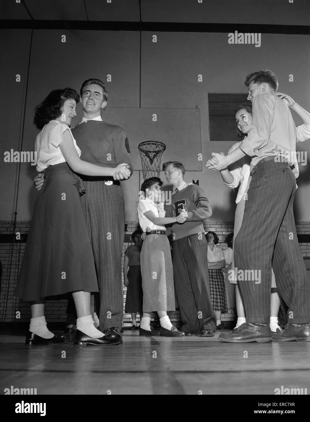 1940s 1950s TEENAGE BOYS AND GIRLS DANCING SLOW DANCE AT PARTY IN HIGH SCHOOL GYMNASIUM Stock Photo