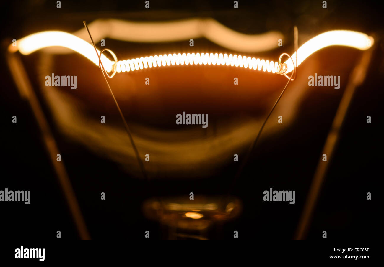 Filament. Incandescent electric light bulb filament, turned on Stock