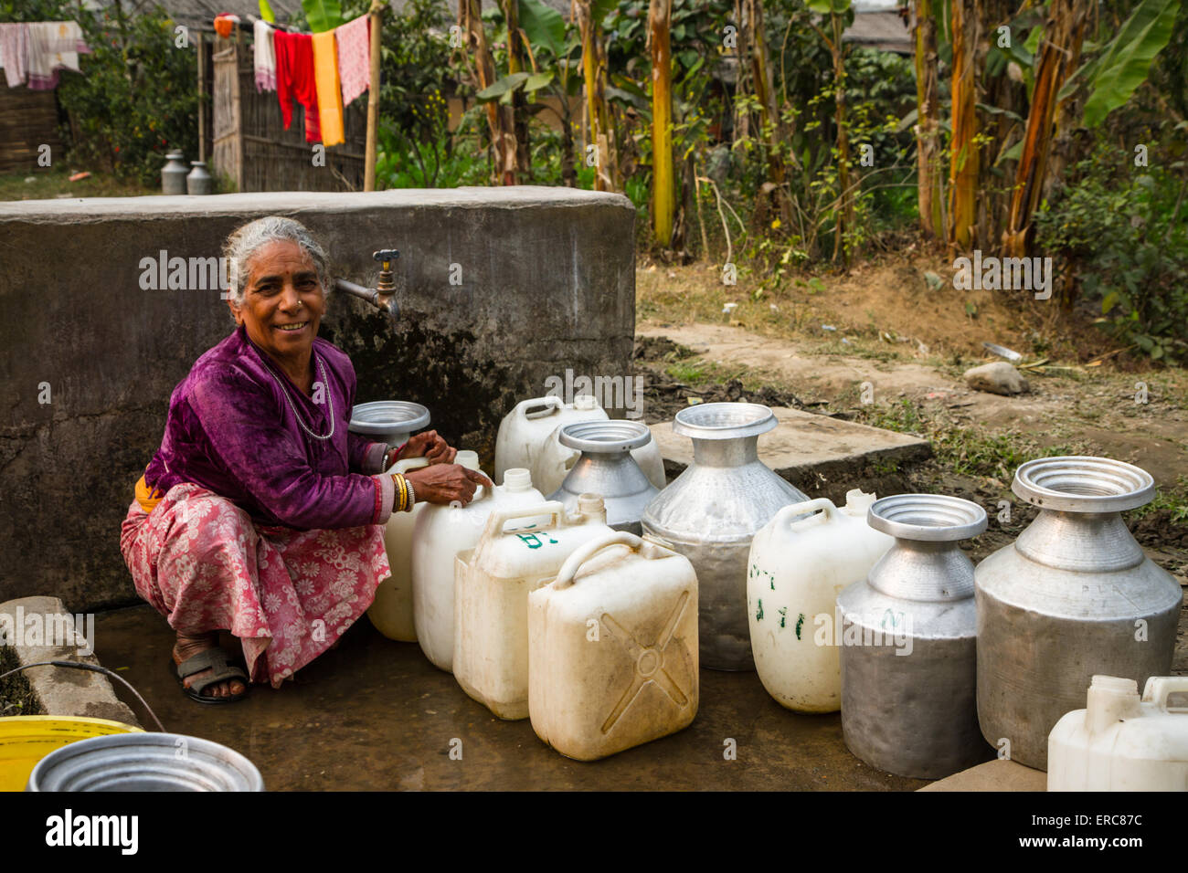 Woman and queue of water containers waiting to be filled when the water comes on in Khudunabari Bhutanese Refugee Camp, Nepal Stock Photo