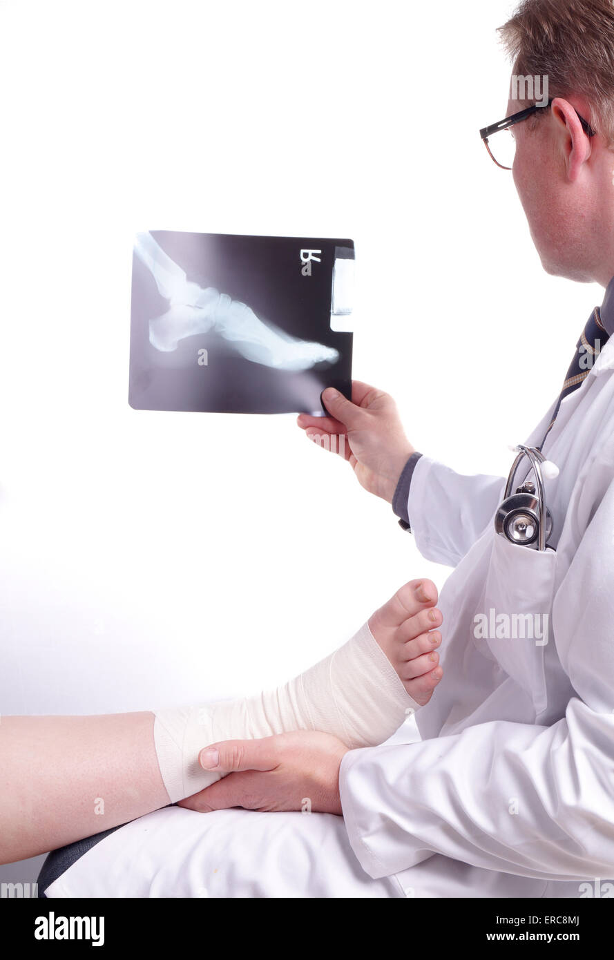 The doctor examines an X-ray picture , while the patient's sprained foot resting in his hand Stock Photo