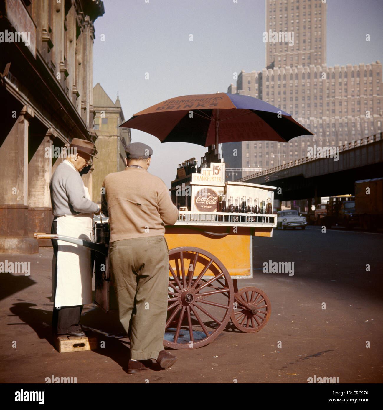1950s MAN HOT DOG VENDOR PUSHCART WITH UMBRELLA SELLING COKES FOR 15 CENTS WEST STREET DOWNTOWN MANHATTAN NEW YORK USA Stock Photo