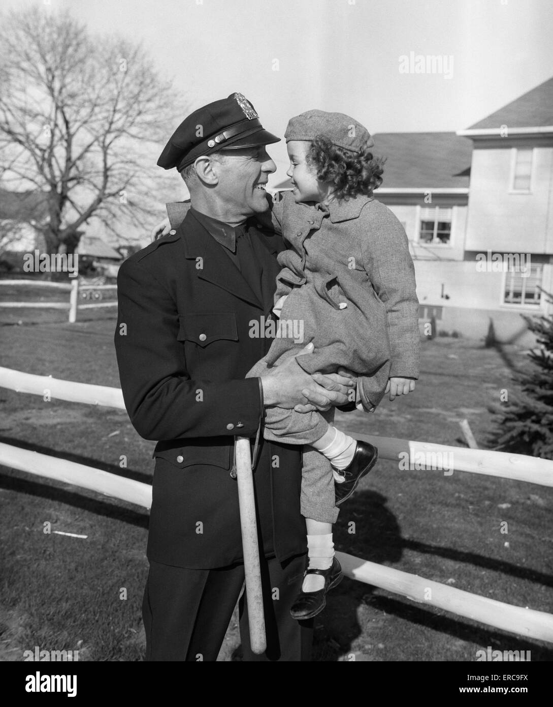 1950s POLICEMAN CARRYING YOUNG GIRL Stock Photo