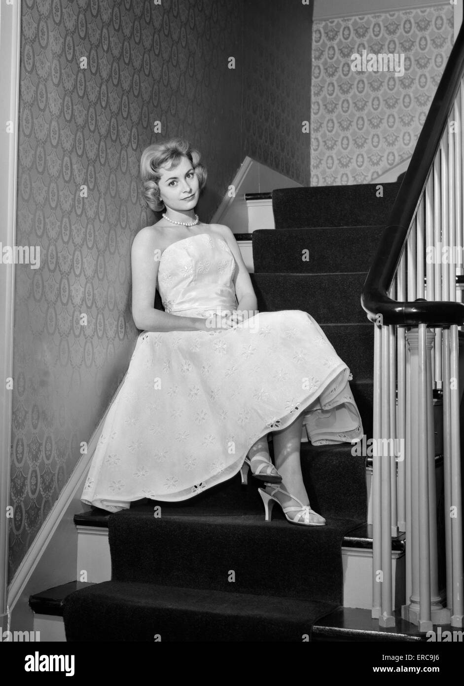 1950s 1960s WOMAN FORMAL COCKTAIL DRESS SITTING ON STAIRS LOOKING SAD WAITING FOR DATE STOOD UP Stock Photo