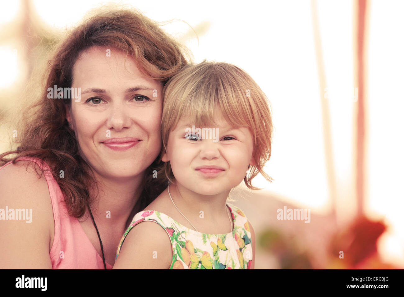 Outdoor summer evening portrait of a real Caucasian family, young mother with her small cute daughter, warm toned photo, old sty Stock Photo