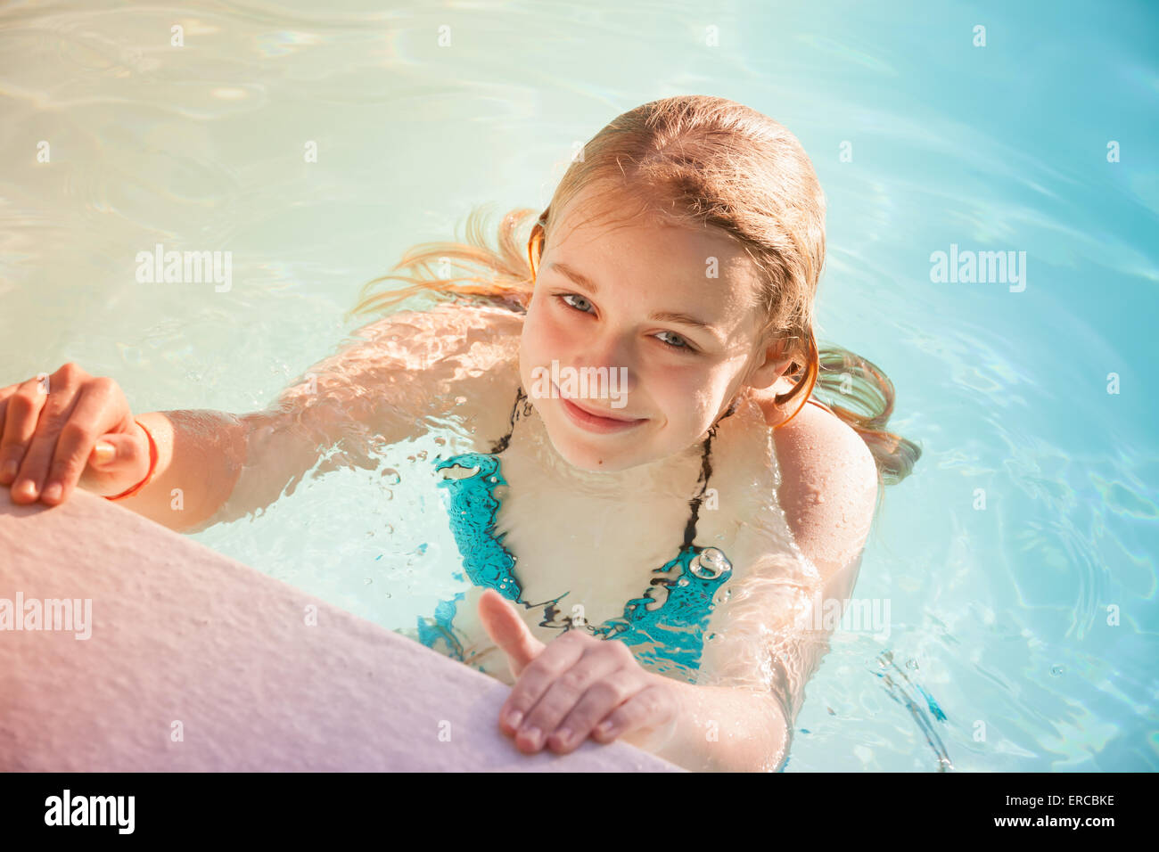 Beautiful teenage blond girl swims in outdoor pool, closeup summer portrait, colorful  toned photo, old style instagram filter e Stock Photo
