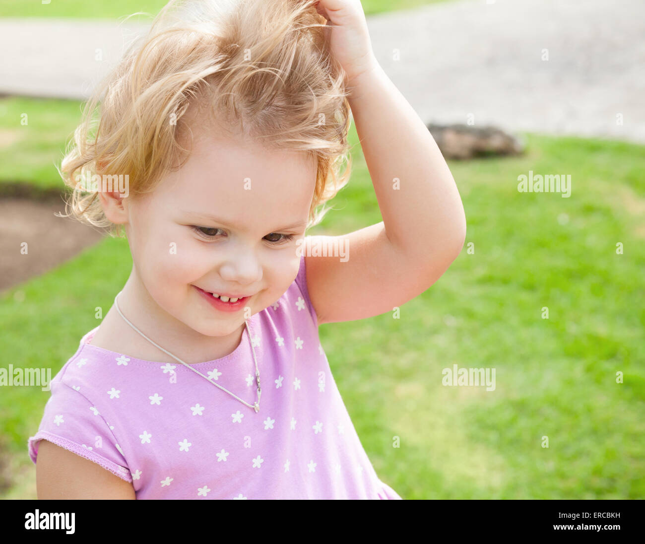 Outdoor summer portrait of cute playful smiling Caucasian blond baby girl in a park Stock Photo