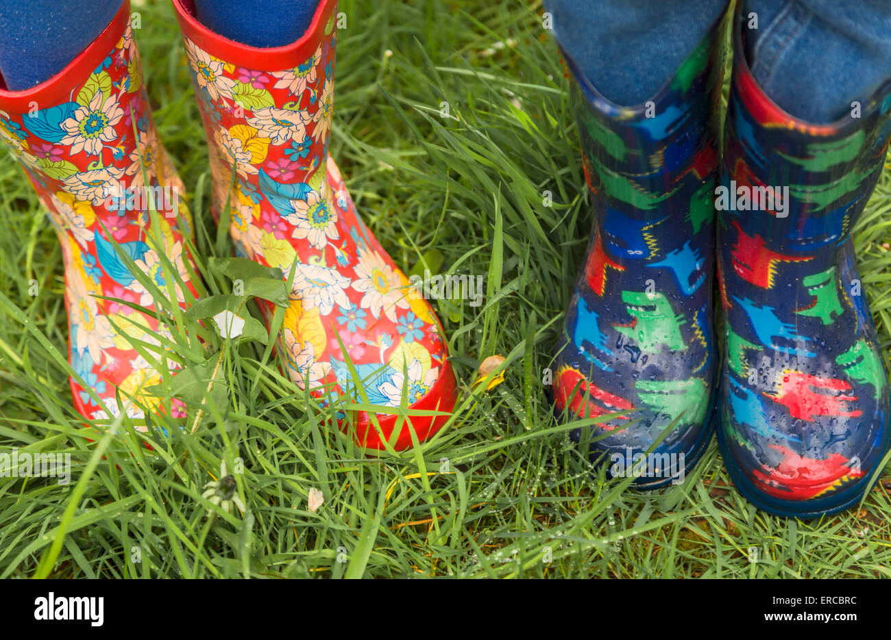 Children wearing colorful gumboots on a rainy day in spring in the garden of Standen House, East Grinstead, Sussex, England, UK. Stock Photo