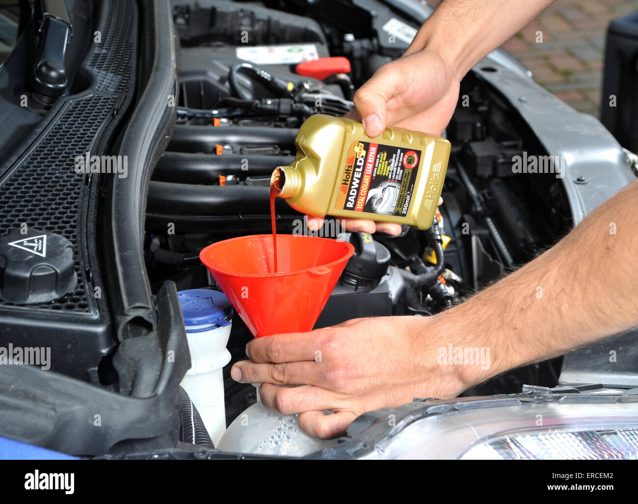 Pouring radiator leak repair liquid into a cars cooling system Stock Photo