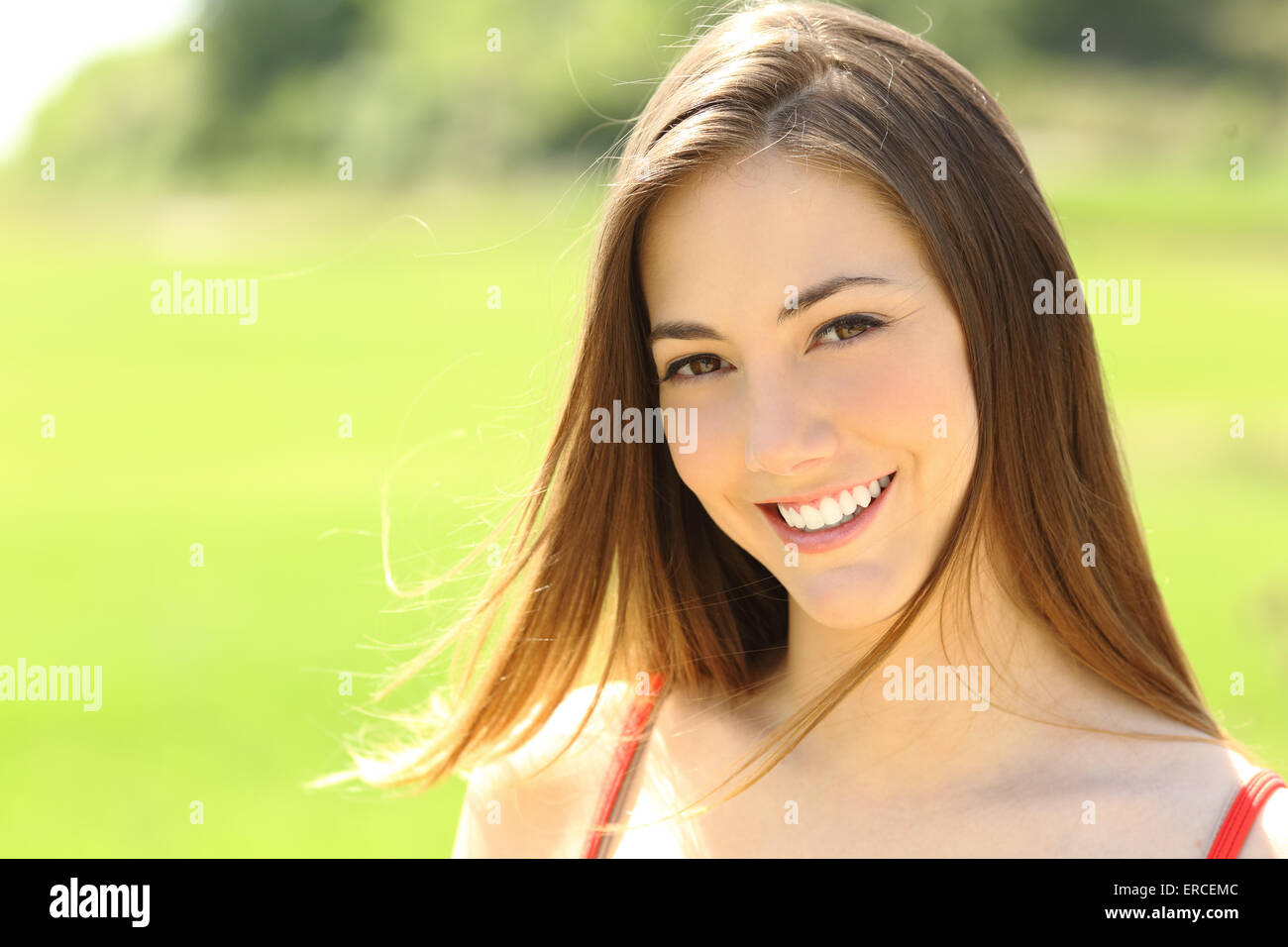 Candid woman with perfect teeth and smile looking you with the wind moving her hair Stock Photo