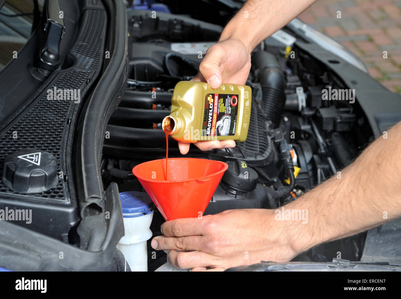 Pouring radiator repair liquid into a car cooling system to plug a leak